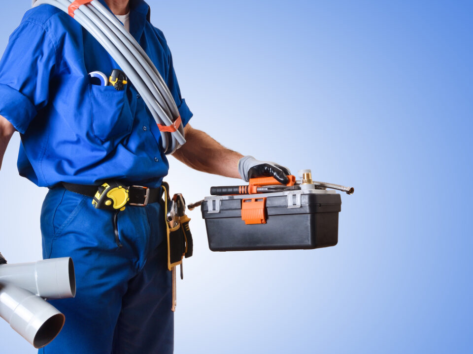 Detail of uniformed plumber with tools and blue isolated background